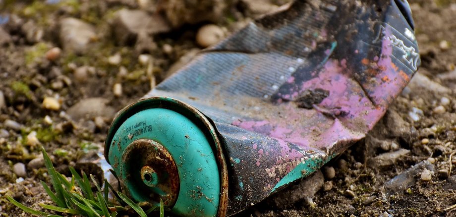 Alte, rostige Sprühdose liegt zerdrückt auf dem Waldboden